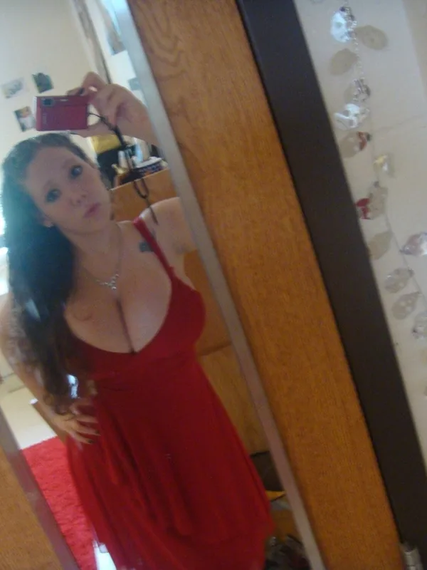Autoportrait dans un miroir, robe rouge, cheveux longs, appareil photo rouge, lumière naturelle, décoration murale